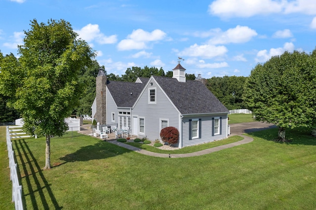 cape cod house featuring a front yard, roof with shingles, fence, and a chimney