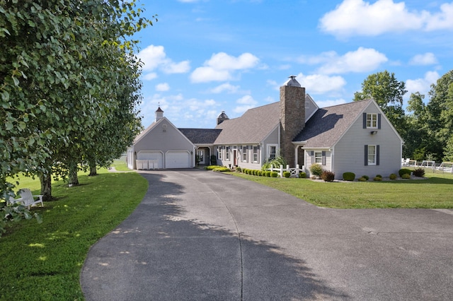 view of front facade with a garage, a chimney, a front lawn, and aphalt driveway