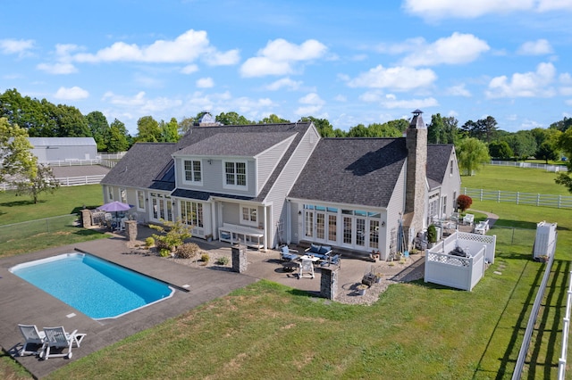 rear view of house with french doors, a yard, a chimney, a patio, and a fenced backyard