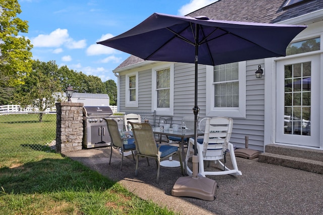 view of patio with entry steps, outdoor dining area, fence, a grill, and exterior kitchen