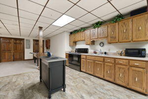 kitchen featuring black appliances, a drop ceiling, brown cabinetry, and light countertops