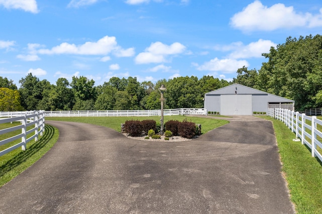 exterior space featuring an outbuilding, a rural view, and driveway