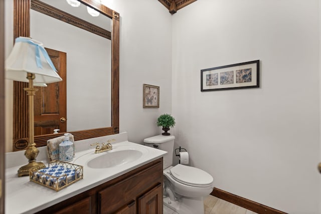 half bathroom featuring vanity, toilet, and baseboards