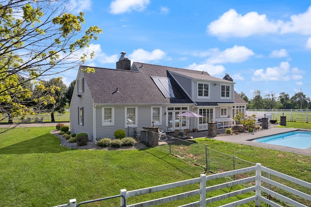 back of house featuring a fenced in pool, a yard, a patio, and french doors