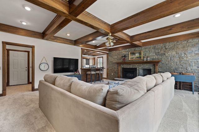 living room with beam ceiling, ceiling fan, coffered ceiling, a stone fireplace, and light colored carpet