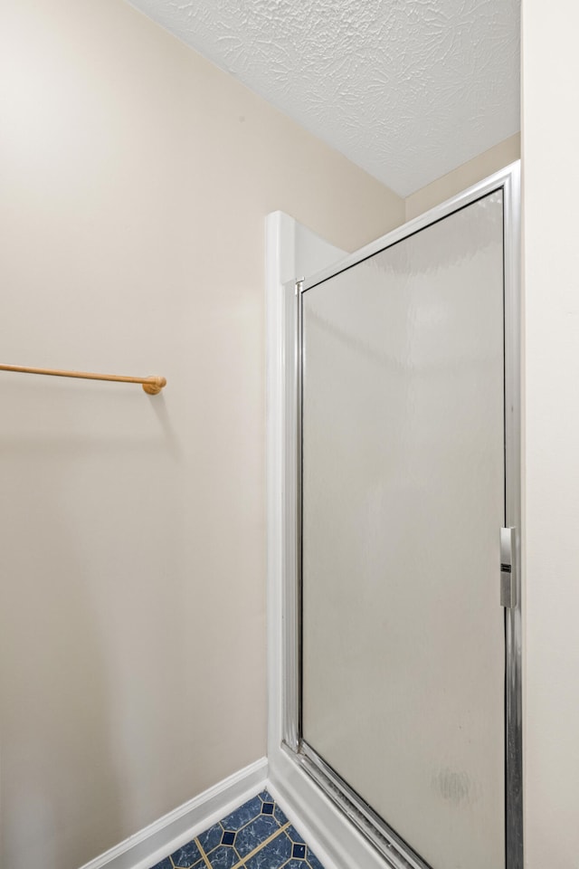 bathroom featuring walk in shower and a textured ceiling