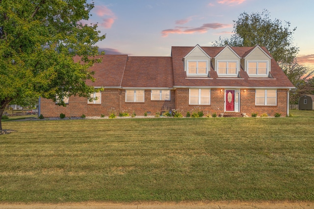 cape cod house featuring a yard