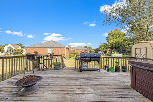 wooden deck featuring an outdoor fire pit, a playground, a storage unit, and a trampoline