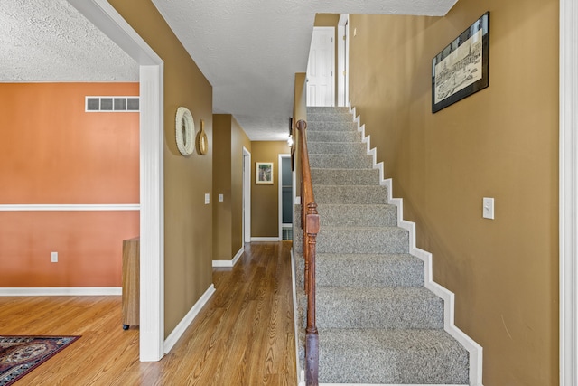 staircase with hardwood / wood-style flooring and a textured ceiling