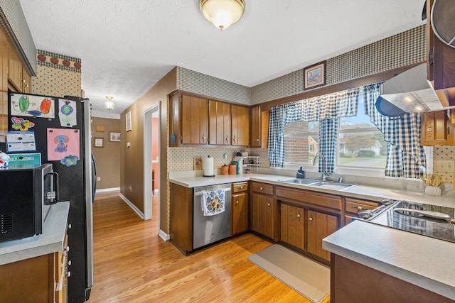 kitchen with sink, a textured ceiling, appliances with stainless steel finishes, light hardwood / wood-style floors, and backsplash