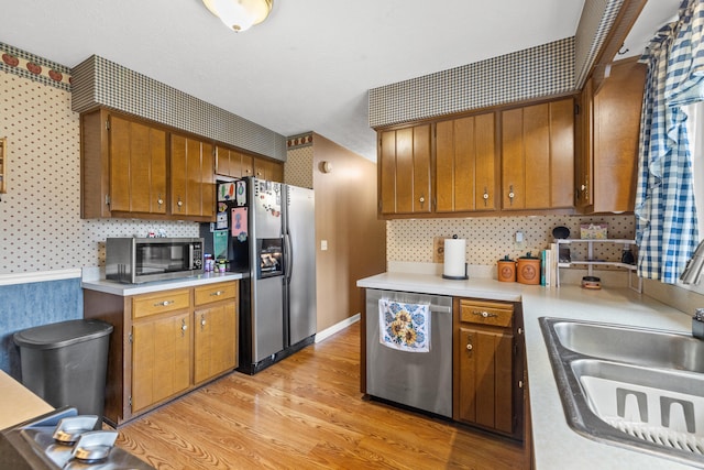 kitchen with sink, light wood-type flooring, and appliances with stainless steel finishes