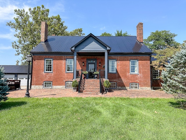 back of house with brick siding, metal roof, and a chimney