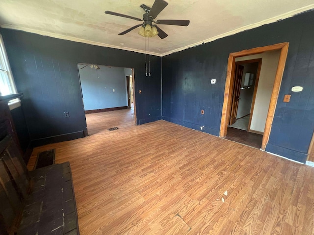 empty room featuring ceiling fan, hardwood / wood-style floors, and ornamental molding