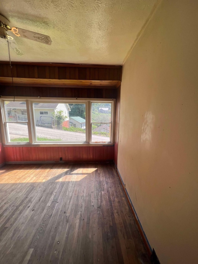 empty room featuring a textured ceiling, plenty of natural light, and hardwood / wood-style floors