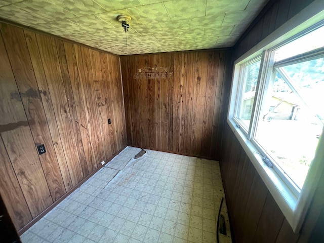 empty room with tile patterned flooring and wooden walls