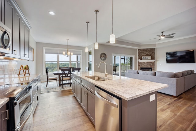 kitchen featuring pendant lighting, decorative backsplash, appliances with stainless steel finishes, a kitchen island with sink, and a sink