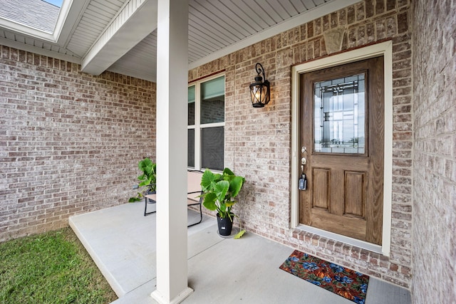 property entrance featuring covered porch and brick siding