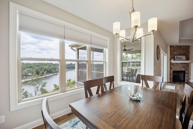 dining area featuring a water view, a fireplace, visible vents, and wood finished floors