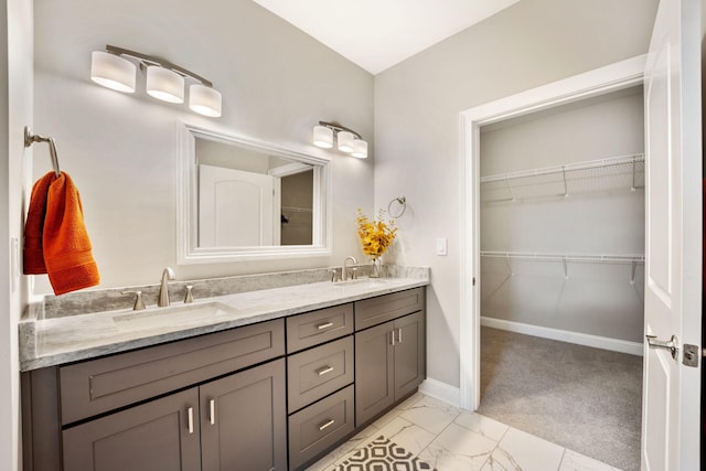 full bathroom featuring marble finish floor, double vanity, a sink, and baseboards