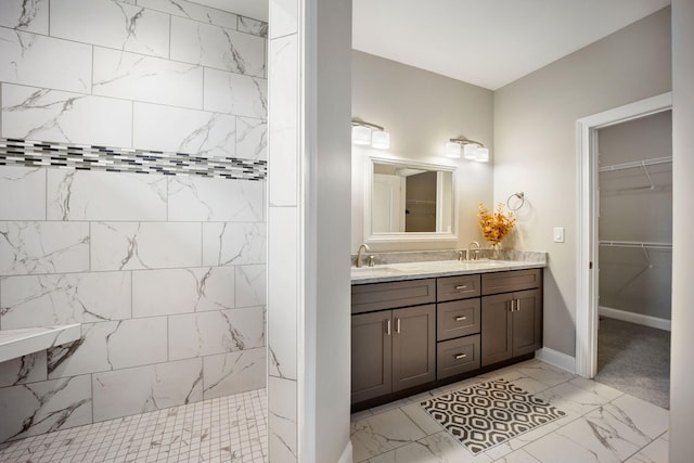 bathroom featuring marble finish floor, walk in shower, a sink, and double vanity