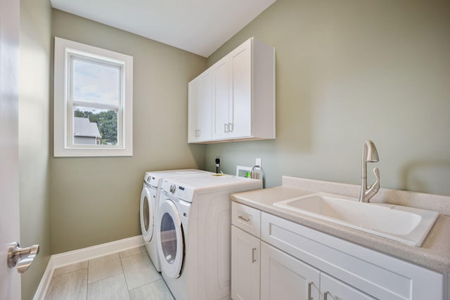 clothes washing area with sink, washer and clothes dryer, and cabinets