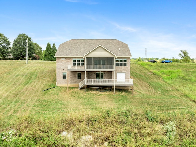 rear view of property with a wooden deck, a sunroom, and a lawn