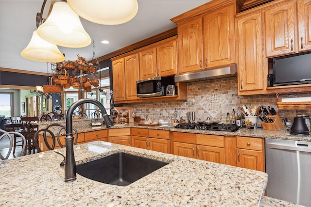 kitchen featuring light stone countertops, backsplash, crown molding, stainless steel appliances, and sink