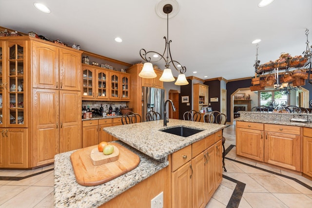 kitchen featuring an island with sink, light stone counters, and stainless steel fridge