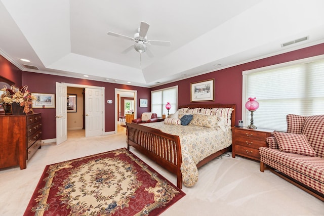 bedroom featuring light colored carpet, ceiling fan, ornamental molding, and a tray ceiling