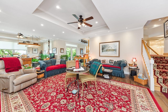 living room featuring a tray ceiling, crown molding, wood-type flooring, and ceiling fan