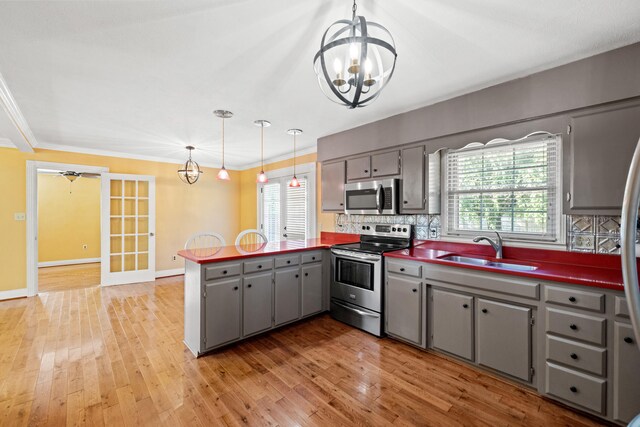 kitchen featuring sink, pendant lighting, kitchen peninsula, light wood-type flooring, and stainless steel appliances