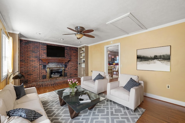 living room featuring wood-type flooring, a brick fireplace, ceiling fan, and crown molding