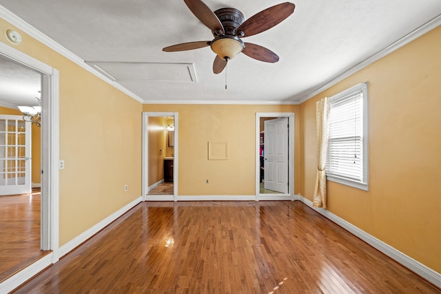 unfurnished bedroom featuring ensuite bathroom, crown molding, wood-type flooring, a closet, and ceiling fan with notable chandelier