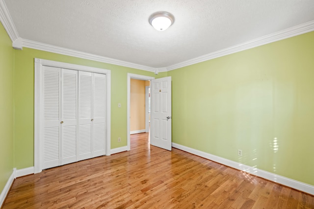 unfurnished bedroom with hardwood / wood-style floors, a textured ceiling, a closet, and crown molding