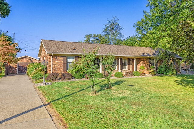 single story home with a front yard, an outbuilding, and a garage