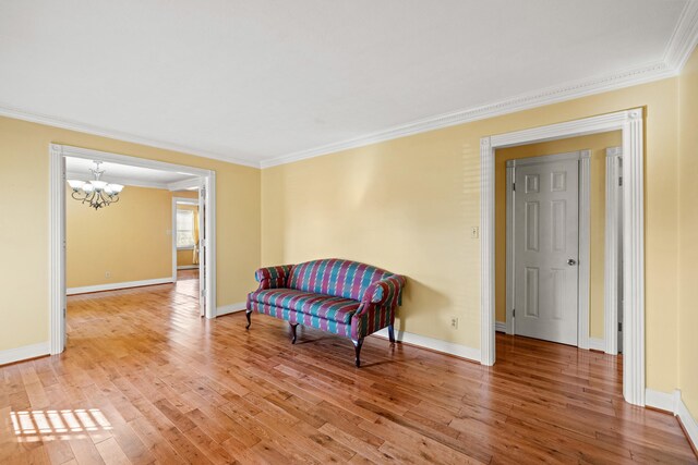 sitting room with hardwood / wood-style floors, an inviting chandelier, and ornamental molding