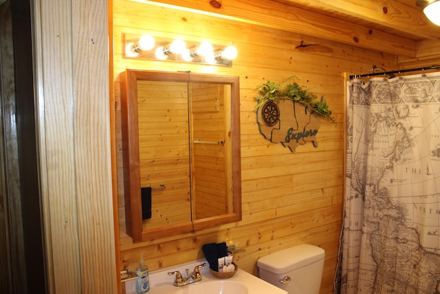 bathroom with a shower with curtain, toilet, wood walls, and sink