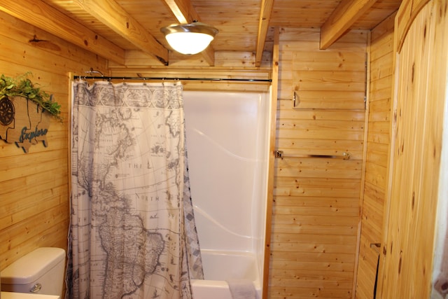 bathroom featuring wood walls, beamed ceiling, wood ceiling, toilet, and shower / bath combo with shower curtain