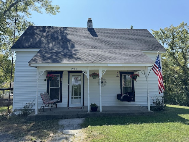 view of front of house with a chimney, roof with shingles, covered porch, and a front lawn