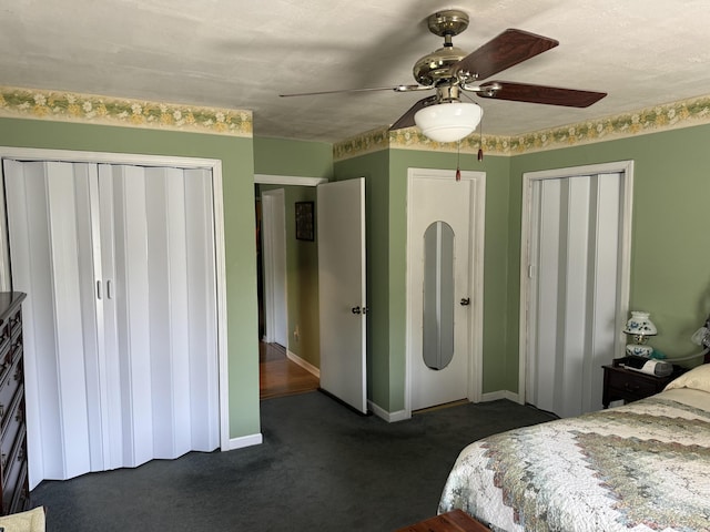 bedroom with baseboards, multiple closets, dark carpet, and ceiling fan