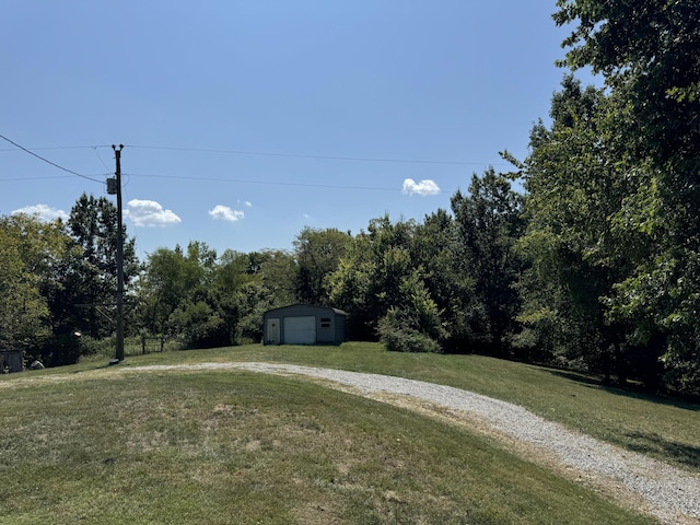 view of yard with an outbuilding, a garage, and driveway