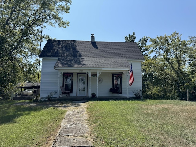 view of front of home with a shingled roof, a front lawn, covered porch, and a chimney