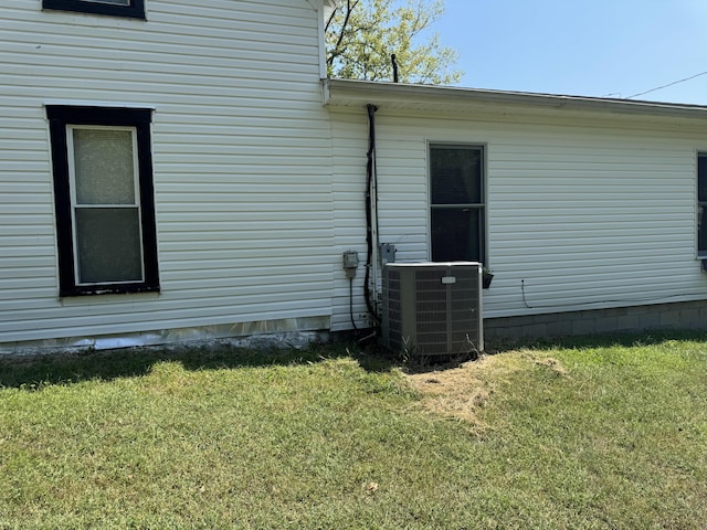 view of side of home featuring a lawn and central AC