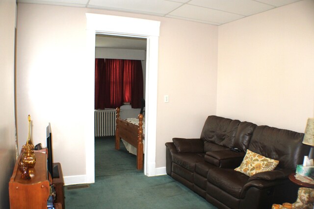 living room featuring a paneled ceiling, carpet flooring, and radiator heating unit