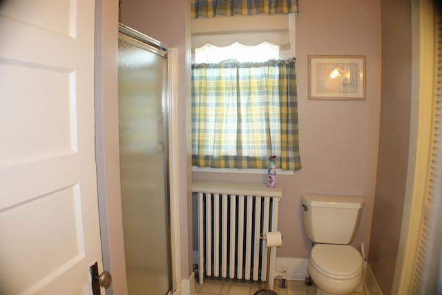 bathroom featuring walk in shower, toilet, radiator heating unit, and tile patterned flooring