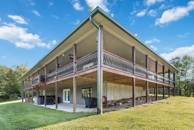 back of property with a lawn, a wooden deck, and a patio area