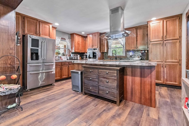 kitchen with stainless steel appliances, sink, dark wood-type flooring, a kitchen island, and island range hood