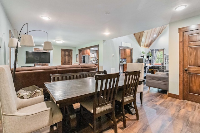 dining space featuring hardwood / wood-style floors and vaulted ceiling with beams