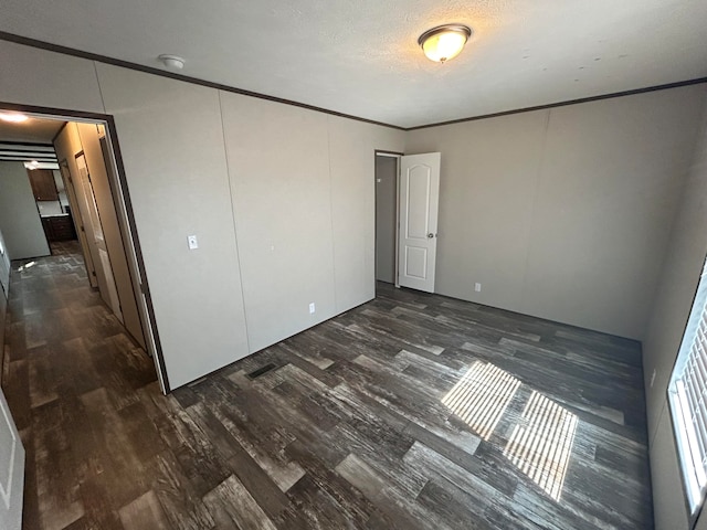 unfurnished bedroom featuring a textured ceiling, crown molding, and dark hardwood / wood-style floors