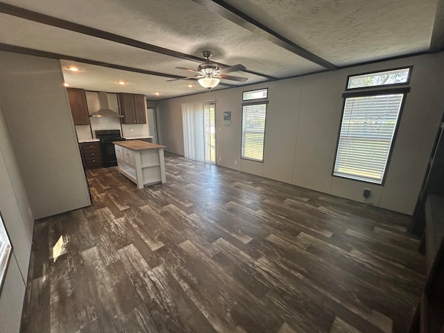 unfurnished living room featuring beamed ceiling, a textured ceiling, ceiling fan, and dark hardwood / wood-style floors